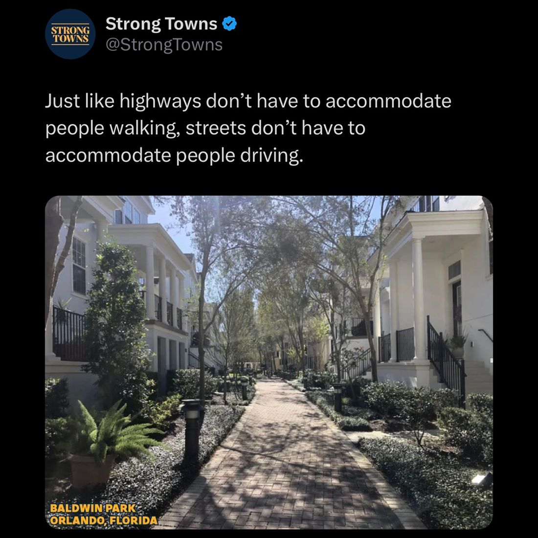 The meme is a tweet from the Twitter account "Strong Towns" with a photo of a residential street in a neighborhood. The photo shows a tree-lined, paved street with houses on either side, and the text "Baldwin Park, Orlando, Florida" is in the bottom left corner. The tweet itself reads: "Just like highways don't have to accommodate people walking, streets don't have to accommodate people driving."